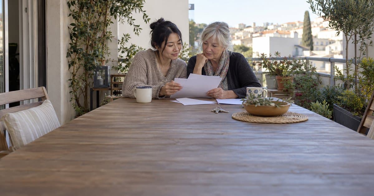 Deux adultes relisent des papiers sur un balcon.